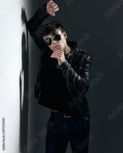 sensual bad guy leaning on wall and touching chin while posing photo