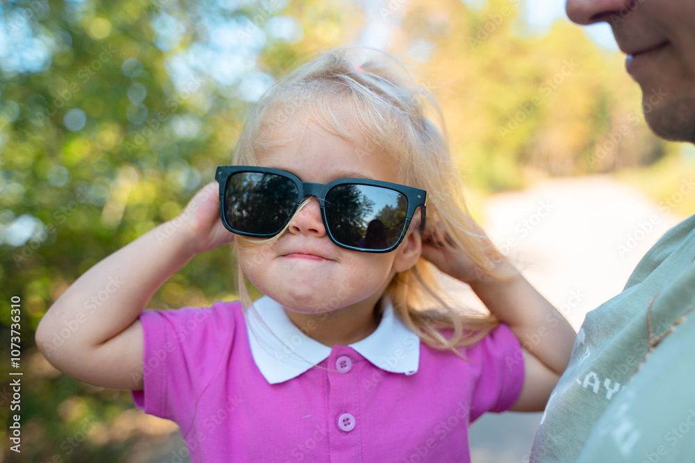 A cute funny child toddler girl put on adult large sunglasses. A cute funny child toddler girl put on adult large sunglasses.