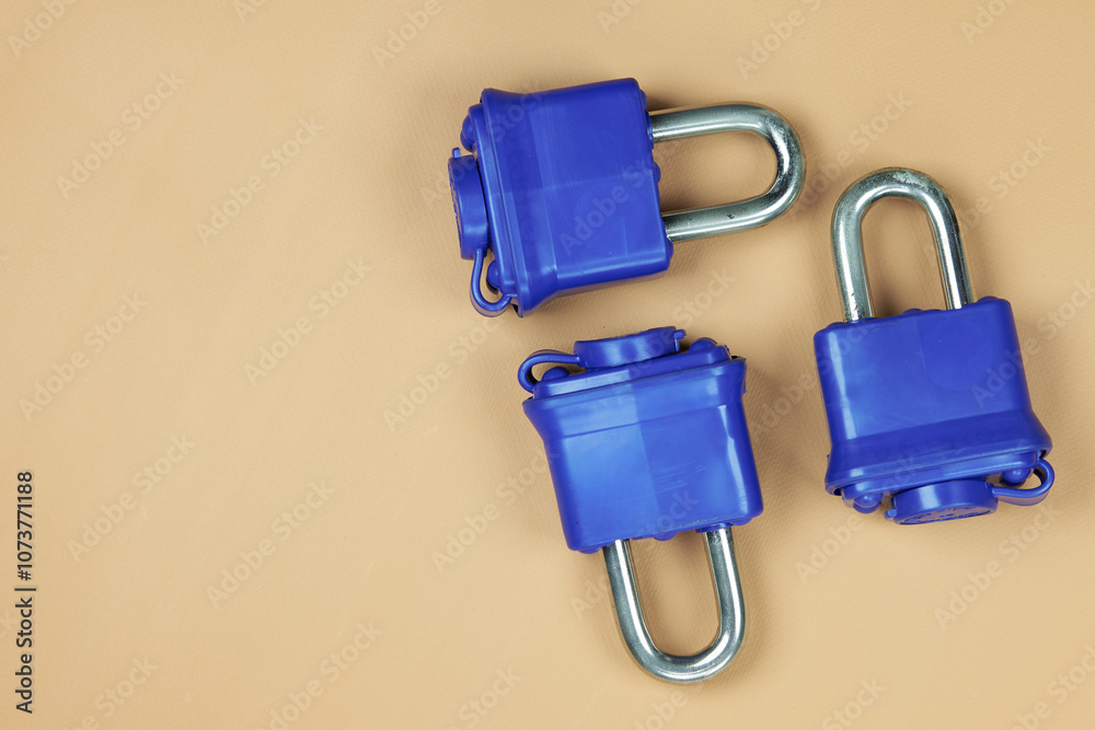 Padlock with blue plastic insulation and key, on a beige background, with free space to put text Padlock with blue plastic insulation and key, on a beige background, with free space to put text