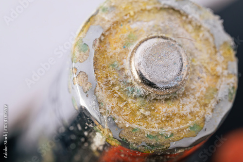 Corroded battery with visible leakage and damage on metal surface. Macro shot. photo