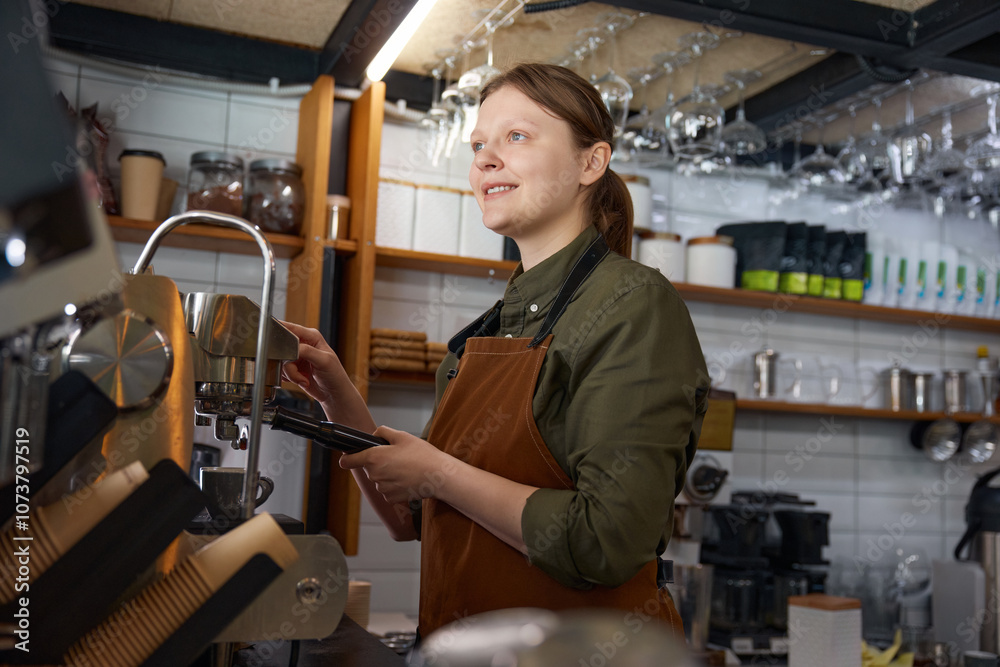 Portrait of dreamy looking woman barista brewing coffee on coffeemaker machine Portrait of dreamy looking woman barista brewing coffee on coffeemaker machine