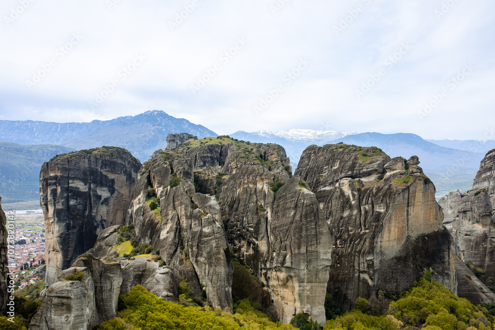 Meteroa, Greece. Majestic rock formations in rise dramatically from the landscape, offering a glimpse into nature's grandeur against the backdrop of distant snow-capped mountains Meteroa, Greece. Majestic rock formations in rise dramatically from the landscape, offering a glimpse into nature's grandeur against the backdrop of distant snow-capped mountains