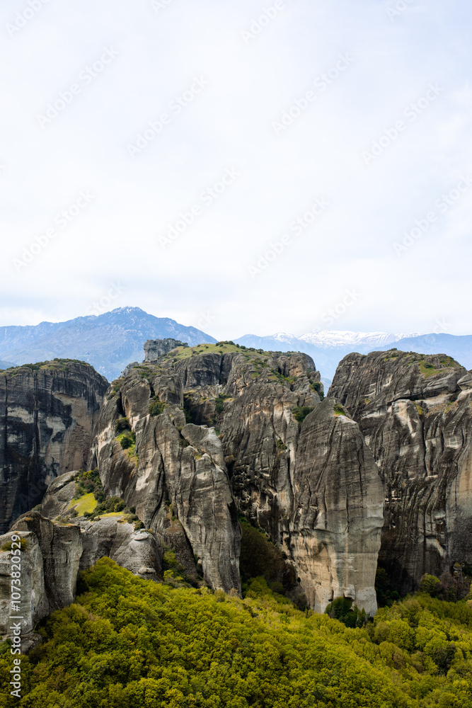 Meteroa, Greece. Majestic rock formations in rise dramatically from the landscape, offering a glimpse into nature's grandeur against the backdrop of distant snow-capped mountains Meteroa, Greece. Majestic rock formations in rise dramatically from the landscape, offering a glimpse into nature's grandeur against the backdrop of distant snow-capped mountains