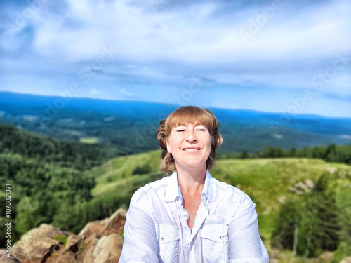 Adventures on a journey. A blogger poses, takes a selfie or podcast in the mountains with a magnificent view