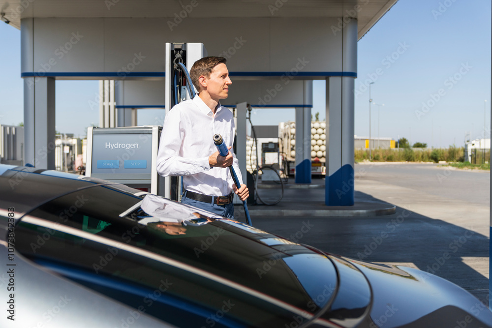 Fototapeta premium Man holds a hydrogen fueling nozzle on a hydrogen filling station. Refueling car with hydrogen fuel.