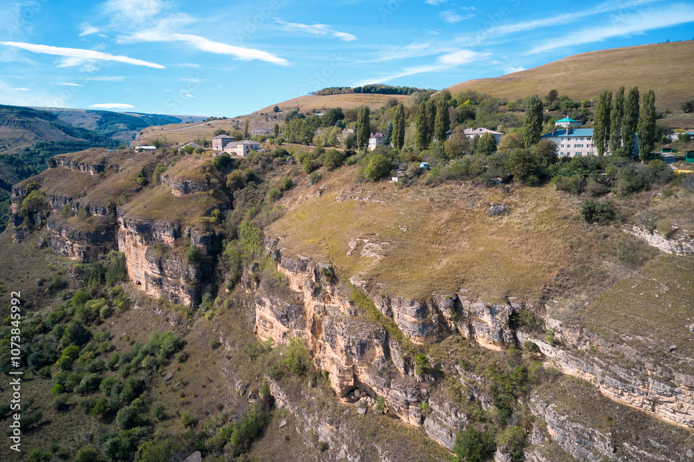 Picturesque panoramic aerial view of a winding rocky gorge with a village on top. Aerial photography. Picturesque panoramic aerial view of a winding rocky gorge with a village on top. Aerial photography.