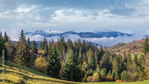 Late autumn mountain morning scene with snow covered tops in far and foggy clouds in valleys. Picturesque traveling, seasonal, nature and countryside beauty concept scene. Carpathians, Ukraine.