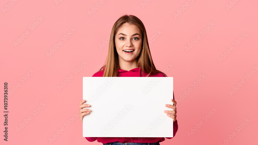 Something new. Happy smiling teenage girl holding white sheet of paper in hands with empty space isolated on pink background, studio shot Something new. Happy smiling teenage girl holding white sheet of paper in hands with empty space isolated on pink background, studio shot