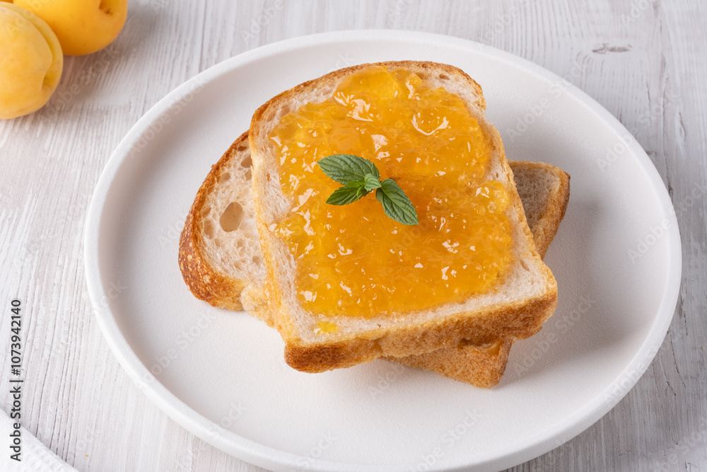 Toasts with tasty apricot jam on a white wooden table Toasts with tasty apricot jam on a white wooden table