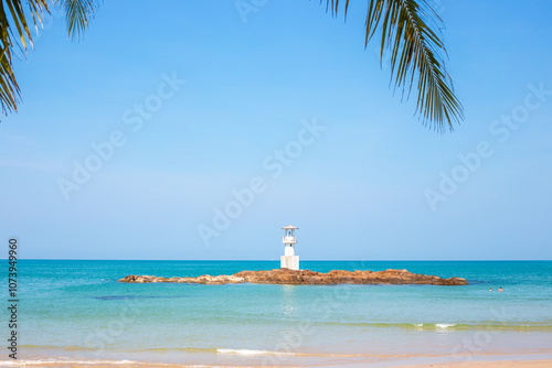 White lighthouse on rocky shoal in sea on tropical coast. Seascape. photo