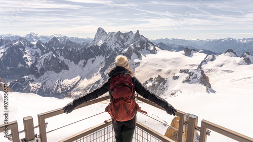 Woman with backpack on blanket with open arms contemplating the snowy mountain range