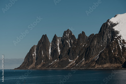 Beautiful view of high rocky mountains, on which snow remained in places, next to them the blue sea photo