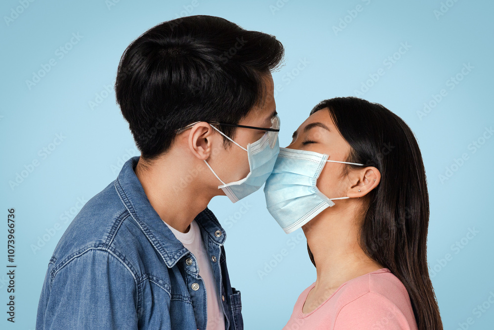 Romantic Young Chinese Couple Kissing In Protective Medical Face Masks Against Virus Spread, Standing Over Light Studio Background, Free Space Romantic Young Chinese Couple Kissing In Protective Medical Face Masks Against Virus Spread, Standing Over Light Studio Background, Free Space
