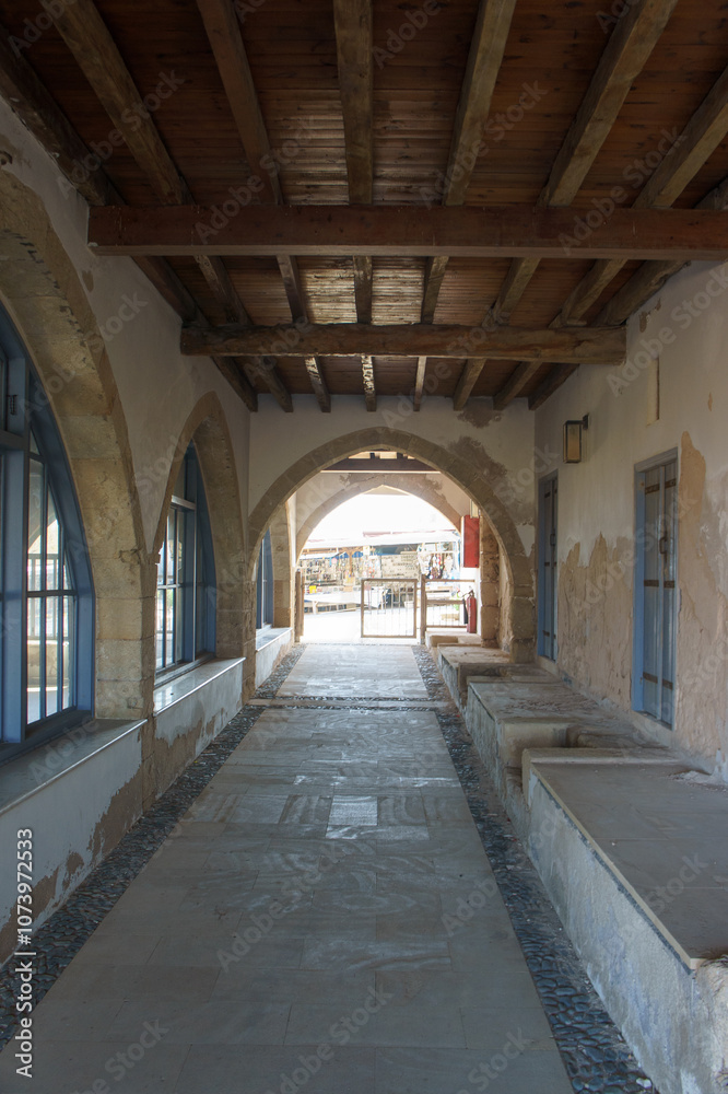 A tranquil corridor leads to a sunlit courtyard in a historic building during the afternoon. A tranquil corridor leads to a sunlit courtyard in a historic building during the afternoon.