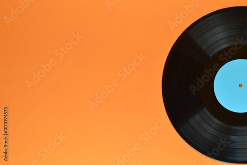 old black vinyl record with blank cyan label half on orange background