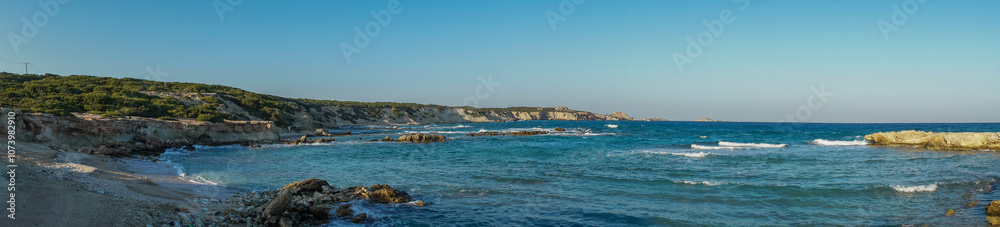 Serenity at the shoreline: tranquil waves caress a sunlit rocky beach on a beautiful afternoon. Serenity at the shoreline: tranquil waves caress a sunlit rocky beach on a beautiful afternoon.