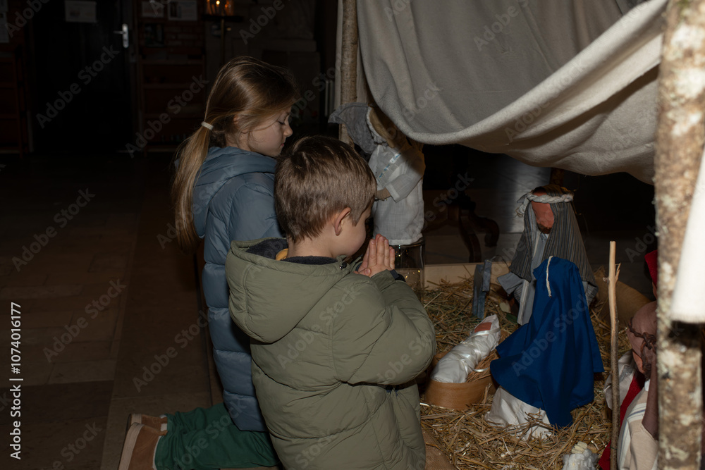A child praying near a Christmas nativity scene with baby Jesus Creche Figurines
