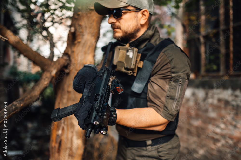 Fototapeta premium Soldier holding submachine gun with tactical gear in urban environment