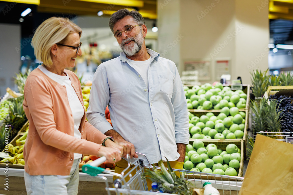 Fototapeta premium Senior couple choosing fruits and vegetables at grocery store