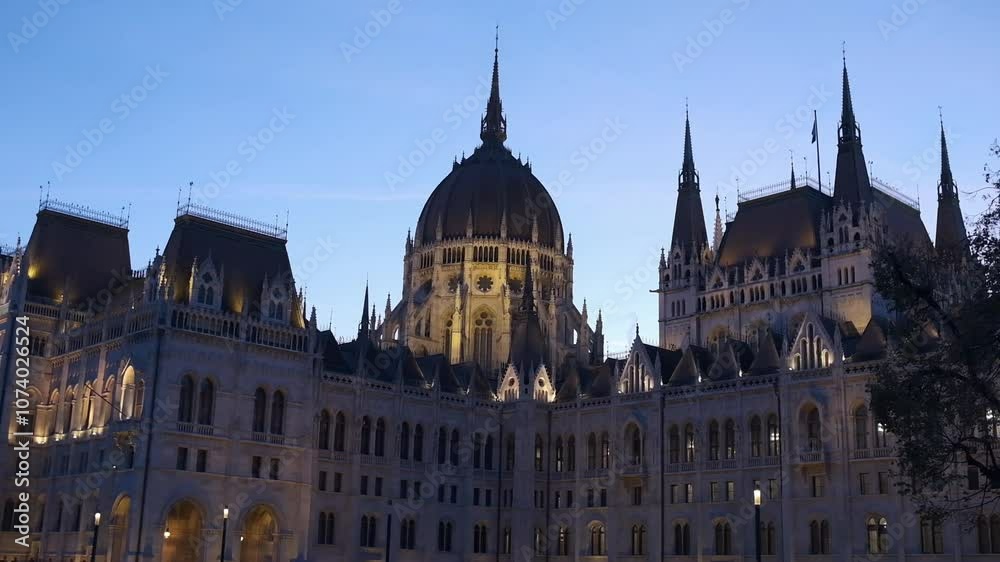 The historic Hungarian Parliament building illuminated at twilight. A side view of the tower against a twilight sky in the background.