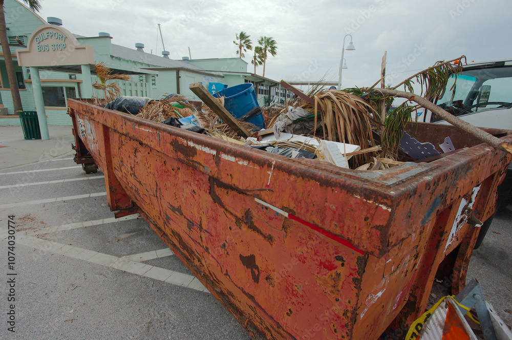 Roll-off Trash container and Green palm trees in Parking Lot Trash Beach damaged piled storm surge after hurricanes Helene and Milton at Gulfport Beach in Florida. Debris, sand, orange sign and tem Roll-off Trash container and Green palm trees in Parking Lot Trash Beach damaged piled storm surge after hurricanes Helene and Milton at Gulfport Beach in Florida. Debris, sand, orange sign and tem