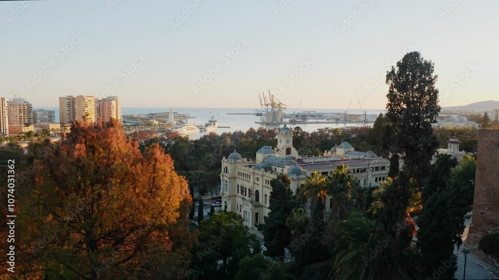 Aerial view of Malaga, Spain, featuring the port with cruise ships, industrial cranes, and the cityscape. Green parks and mountains are visible under a clear blue sky, urban and coastal scenery. Aerial view of Malaga, Spain, featuring the port with cruise ships, industrial cranes, and the cityscape. Green parks and mountains are visible under a clear blue sky, urban and coastal scenery.