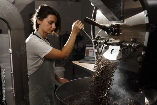 Fotografia Coffee roaster checks freshly roasted coffee beans in the factory