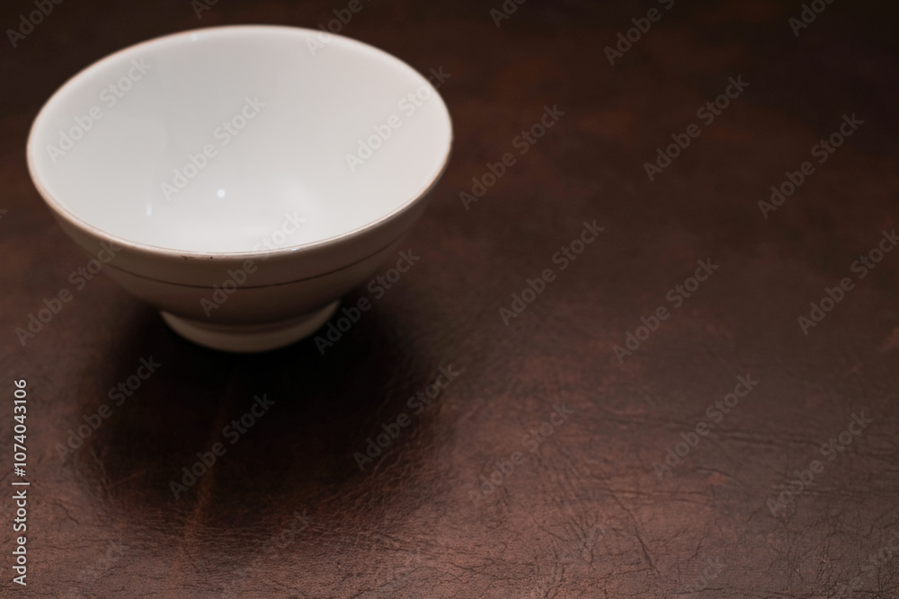Overhead view of a mini white ceramic bowl on a brown background, Top view of a white ceramic mixing bowl, Flat lay of ceramic batter bowl Overhead view of a mini white ceramic bowl on a brown background, Top view of a white ceramic mixing bowl, Flat lay of ceramic batter bowl
