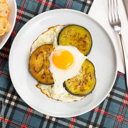 Healthy lunch of pan fried eggs with liquid yolk and slices of aubergine served on plate .. photo