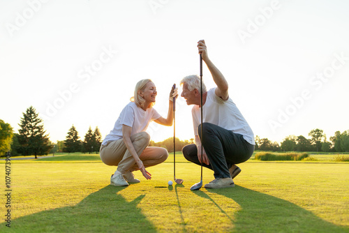 old man and woman in uniform playing golf on golf course at sunset, elderly couple having active outdoor recreation and doing sports, grandpa and grandma holding clubs and pointing where to hit the