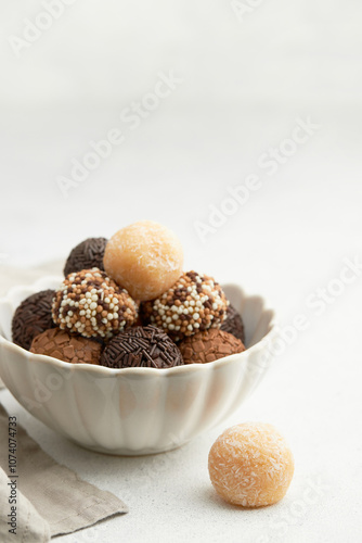 Typical Brazilian sweet brigadeiro. A heap of assorted flavors of candies on a white table with copy space