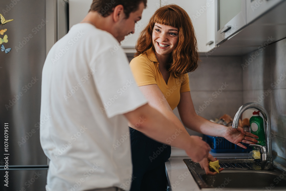 Obraz premium Happy couple washing dishes together in a modern kitchen. They are smiling and enjoying teamwork in their daily chores, creating a warm and cooperative atmosphere at home.