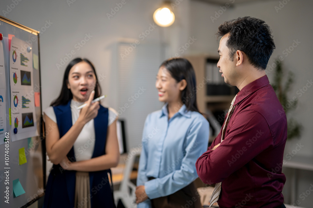 Obraz premium A group of people are standing around a white board with a lot of graphs on it