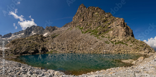 Serene mountain lake with crystal clear water reflecting dramatic cliffs and snow capped peaks in a pristine alpine environment, surrounded by rugged terrain and untouched nature