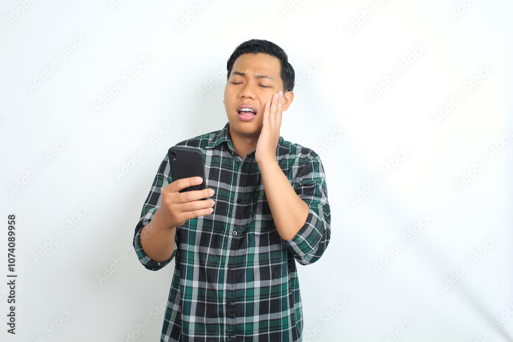 asian man suffering tootache while talking on smartphone isolated on white background asian man suffering tootache while talking on smartphone isolated on white background