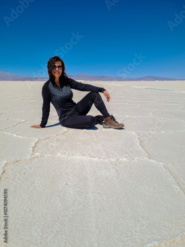 Woman tourist dressed in black sitting in a salt flat in northern Argentina