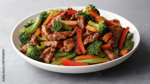 A vibrant stir-fry featuring colorful vegetables and tender beef, served in a large white bowl.