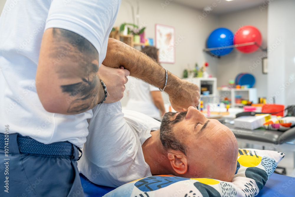 Osteopath practising physiotherapy on a couch to a man's shoulder Osteopath practising physiotherapy on a couch to a man's shoulder