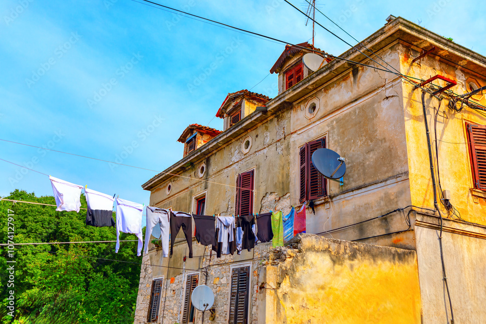 Building exterior featuring colorful clothes hanging on a line. Garments hanging on a clothesline, showcasing everyday life in the city