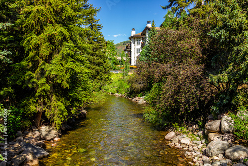 Vail, Colorado ski resort town with Gore creek river clear water by lodge building in summer with green mountain pine forest