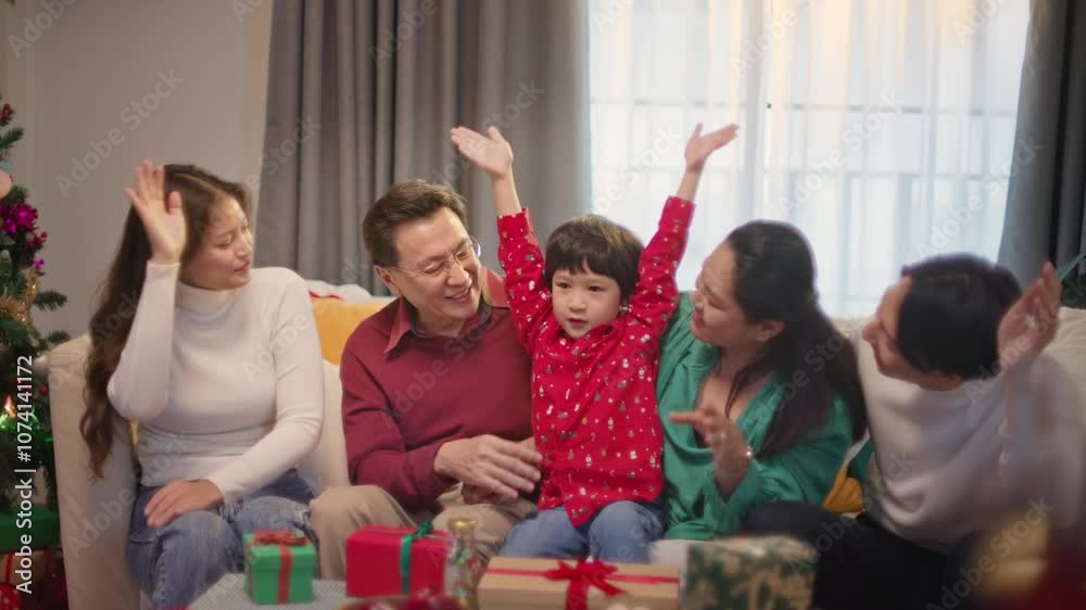 Happy Asian family is sitting on the couch in living room on Christmas morning celebrating holiday Together. Smiling young parent with little child celebrate Xmas and New Year winter holidays at home. Happy Asian family is sitting on the couch in living room on Christmas morning celebrating holiday Together. Smiling young parent with little child celebrate Xmas and New Year winter holidays at home.
