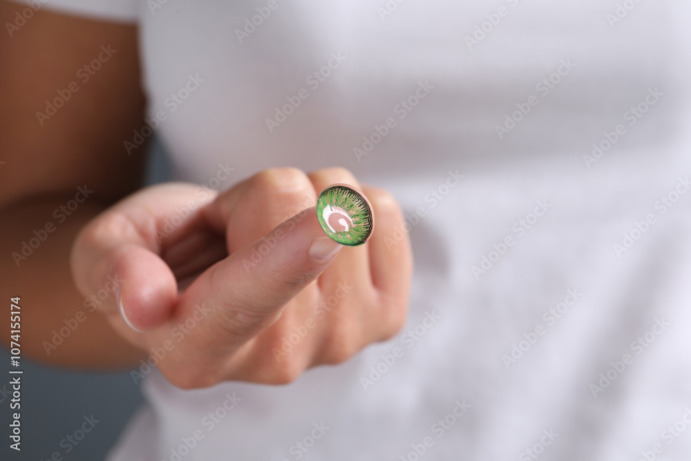 Woman holding color contact lens on light background, closeup Woman holding color contact lens on light background, closeup