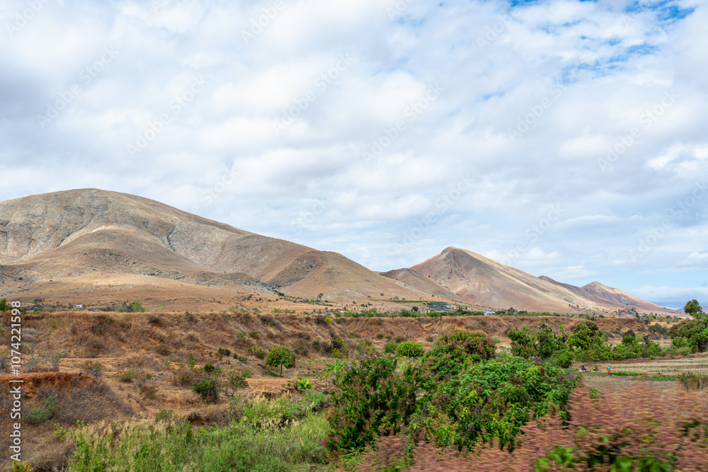 Rolling hills and diverse vegetation under a partly cloudy sky. Jurassic-era geological formations, Isalo National Park, Madagascar. Rolling hills and diverse vegetation under a partly cloudy sky. Jurassic-era geological formations, Isalo National Park, Madagascar.