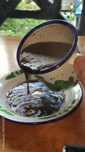 Pouring hot coffee into a saucer from an antique cup