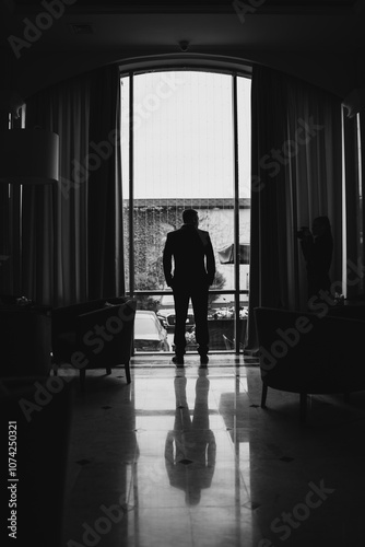 The silhouette of a man in a business suit against the background of a window