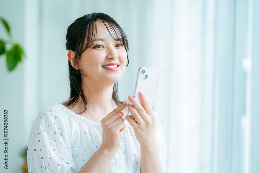 部屋でスマホを操作する若い女性