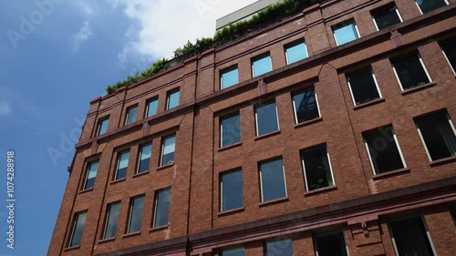 A captivating view of a historic brick building reflecting bright sunlight beautifully under a cloudy sky backdrop