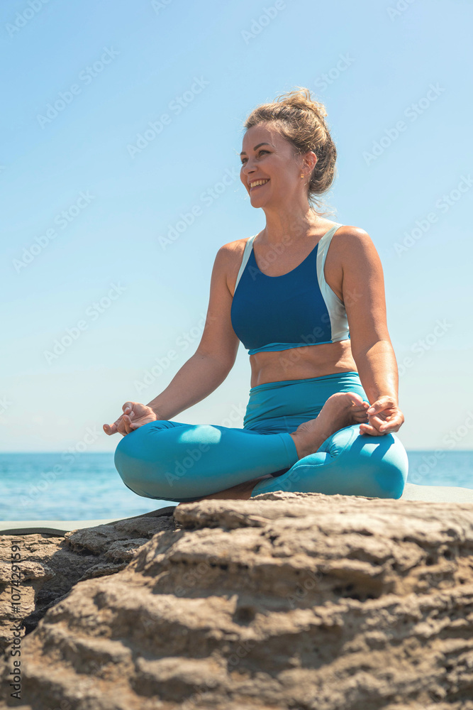 Yoga woman sitting in lotus position namaste hands cliff rock beach sea blue sky Yoga woman sitting in lotus position namaste hands cliff rock beach sea blue sky