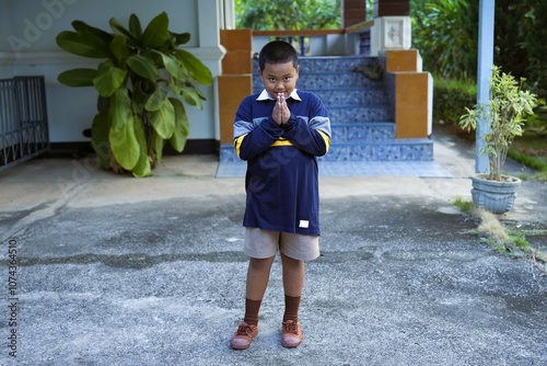 A smiling boy raises his hand to say hello in Thai style.