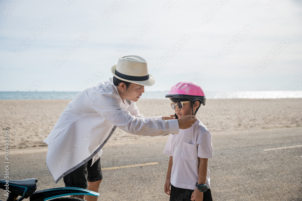 In the warm sunlight of beach day father dons a safety helmet offering inspiration and safety he teaches his cheerful son exciting skill of riding a bicycle a beautiful moment of family connection. In the warm sunlight of beach day father dons a safety helmet offering inspiration and safety he teaches his cheerful son exciting skill of riding a bicycle a beautiful moment of family connection.